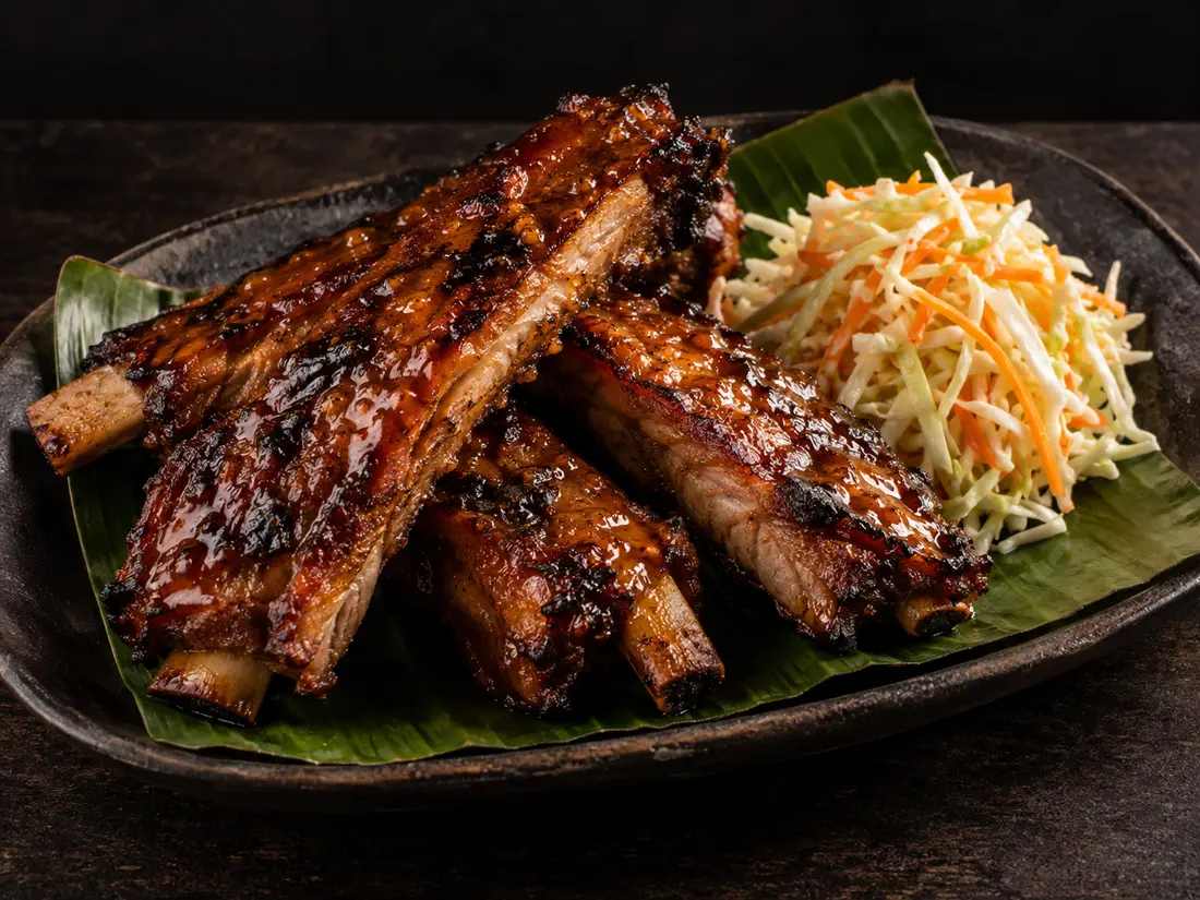 Smoked ribs brushed with mango barbecue glaze beside slaw